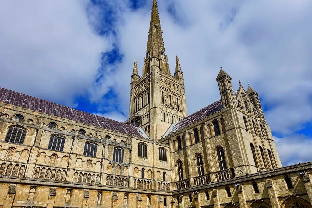 Norwich Cathedral spire and cloister against a blue sky