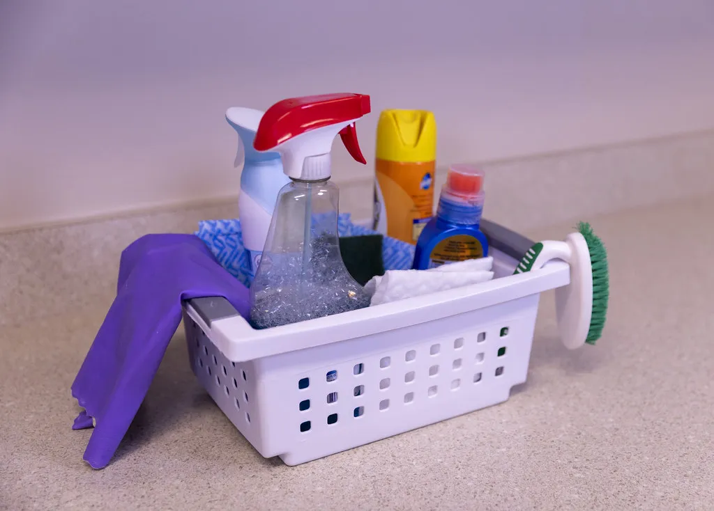 A caddy of cleaning sprays, cloths and brushes with rubber gloves