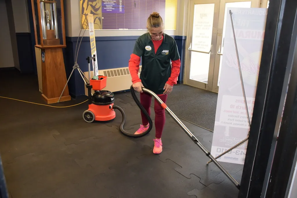 A cleaner vacuuming the entrance floor of a commercial building