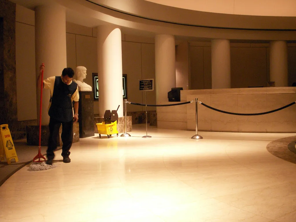 A cleaner mopping the floor of a large reception lobby